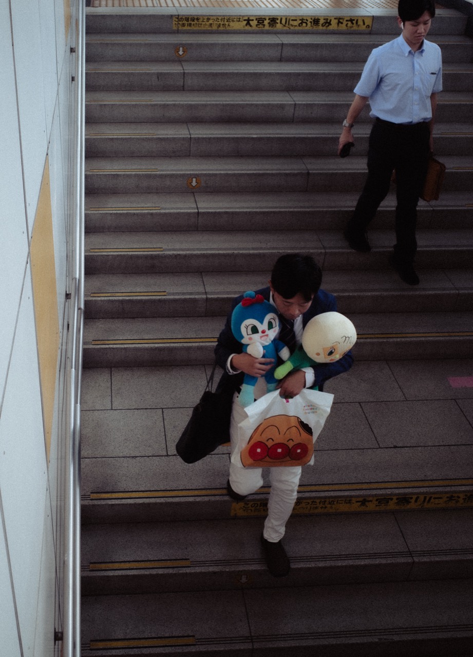 A person carrying two stuffed animals up a station staircase.