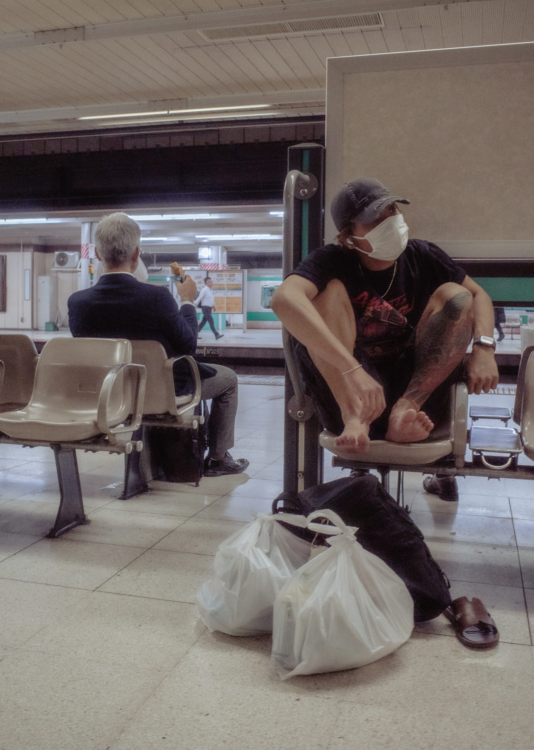 駅のホームで背中合わせに座る二人の男